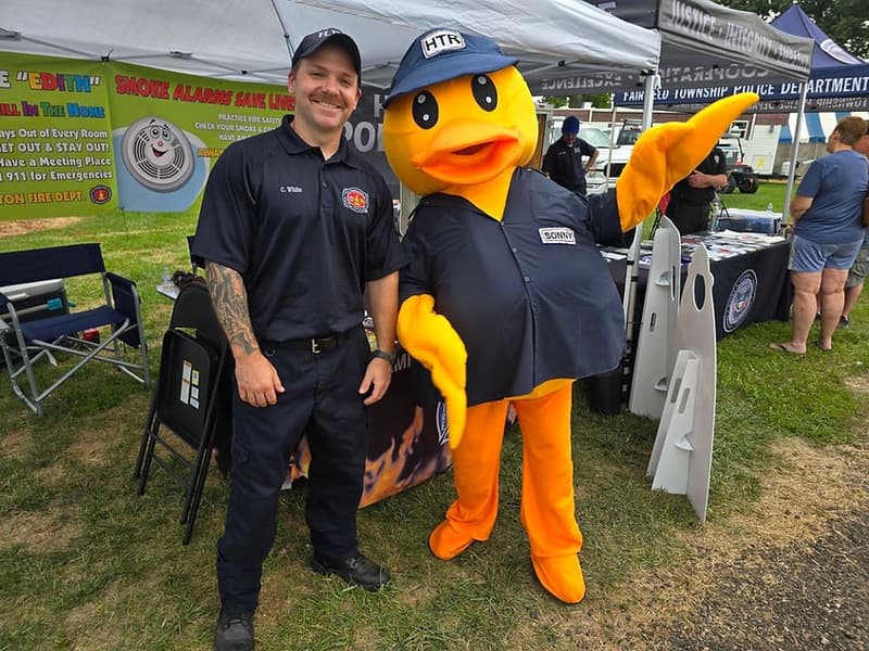 Technician and duck mascot at community event tent